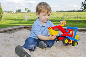 Junge mit Bagger im Sandkasten